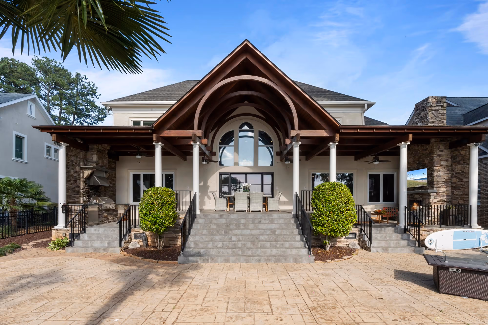 A timber arched portico over a stone entry, with palms on either side.