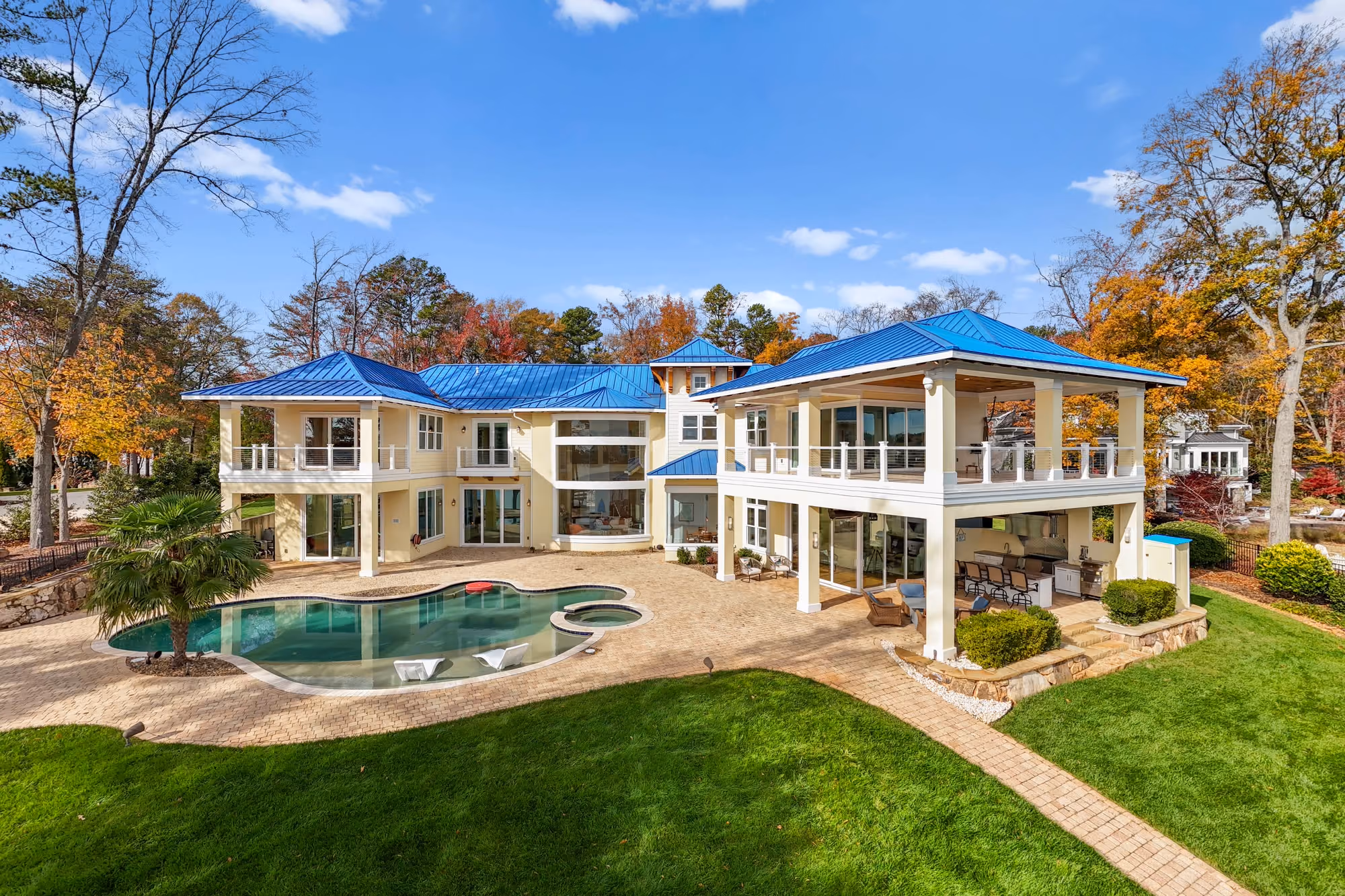 A lake house stepping down to its pool and terrace, from just above the lawn.