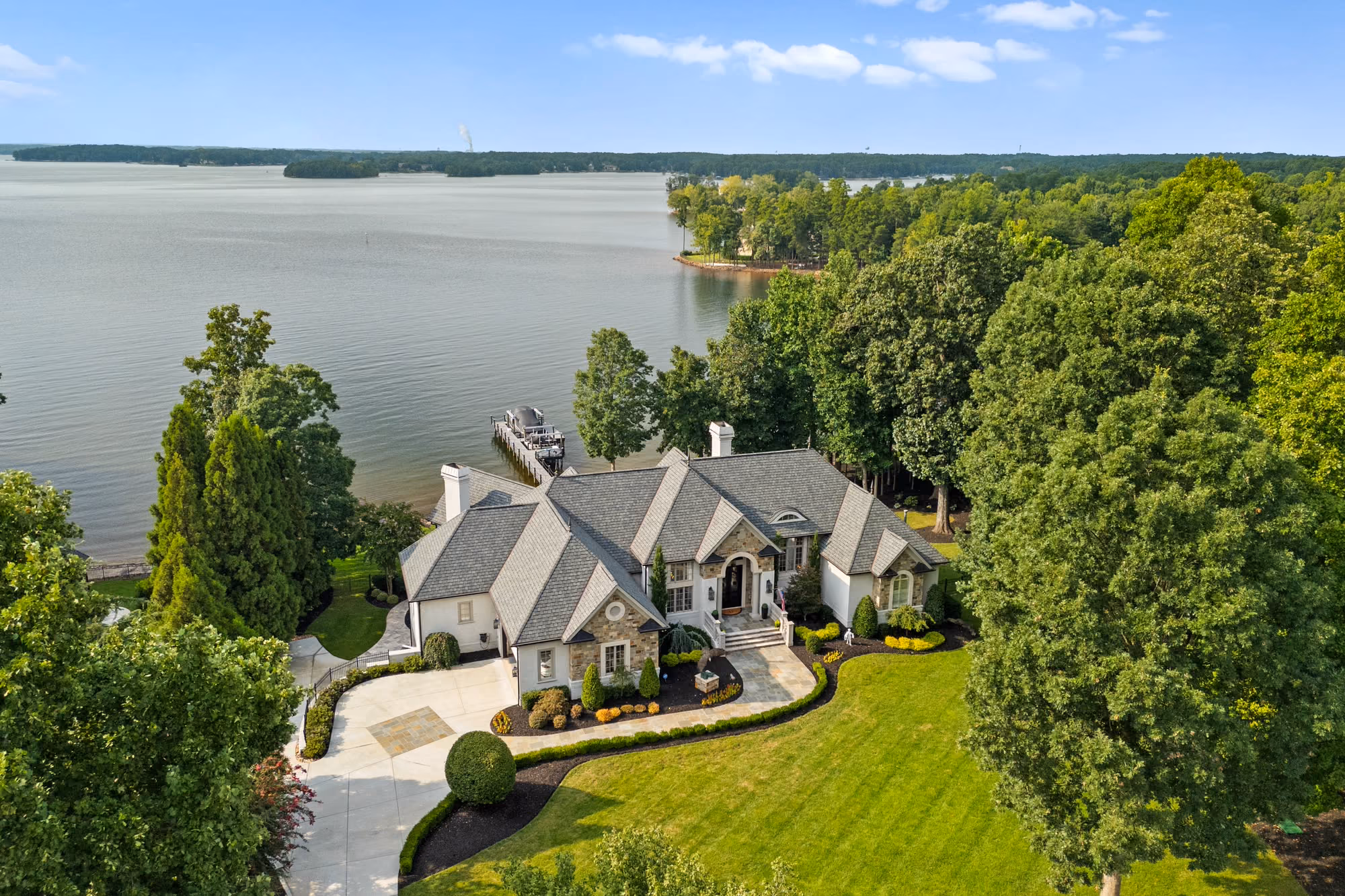 A house on its own point of shoreline, with open water beyond, from the air.