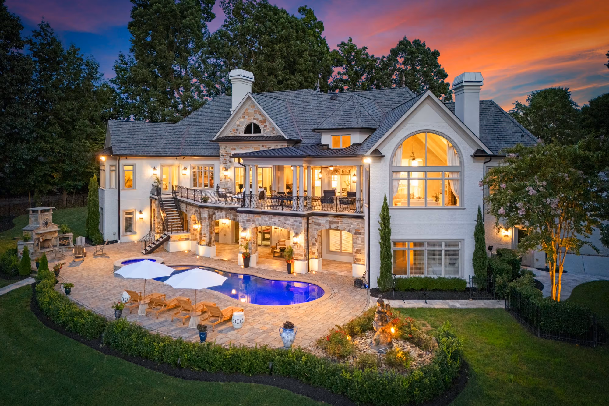 A lakefront house seen from the water at sunset, its windows lit.