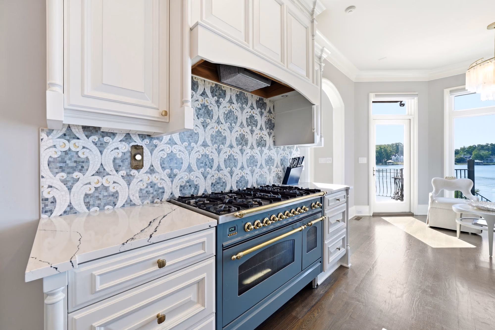 A kitchen with a deep blue range and the lake beyond the window.