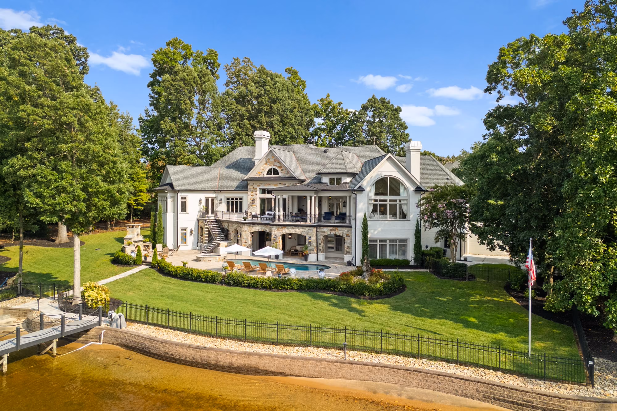 A sloping lawn, a pool and a private dock, seen from the air.