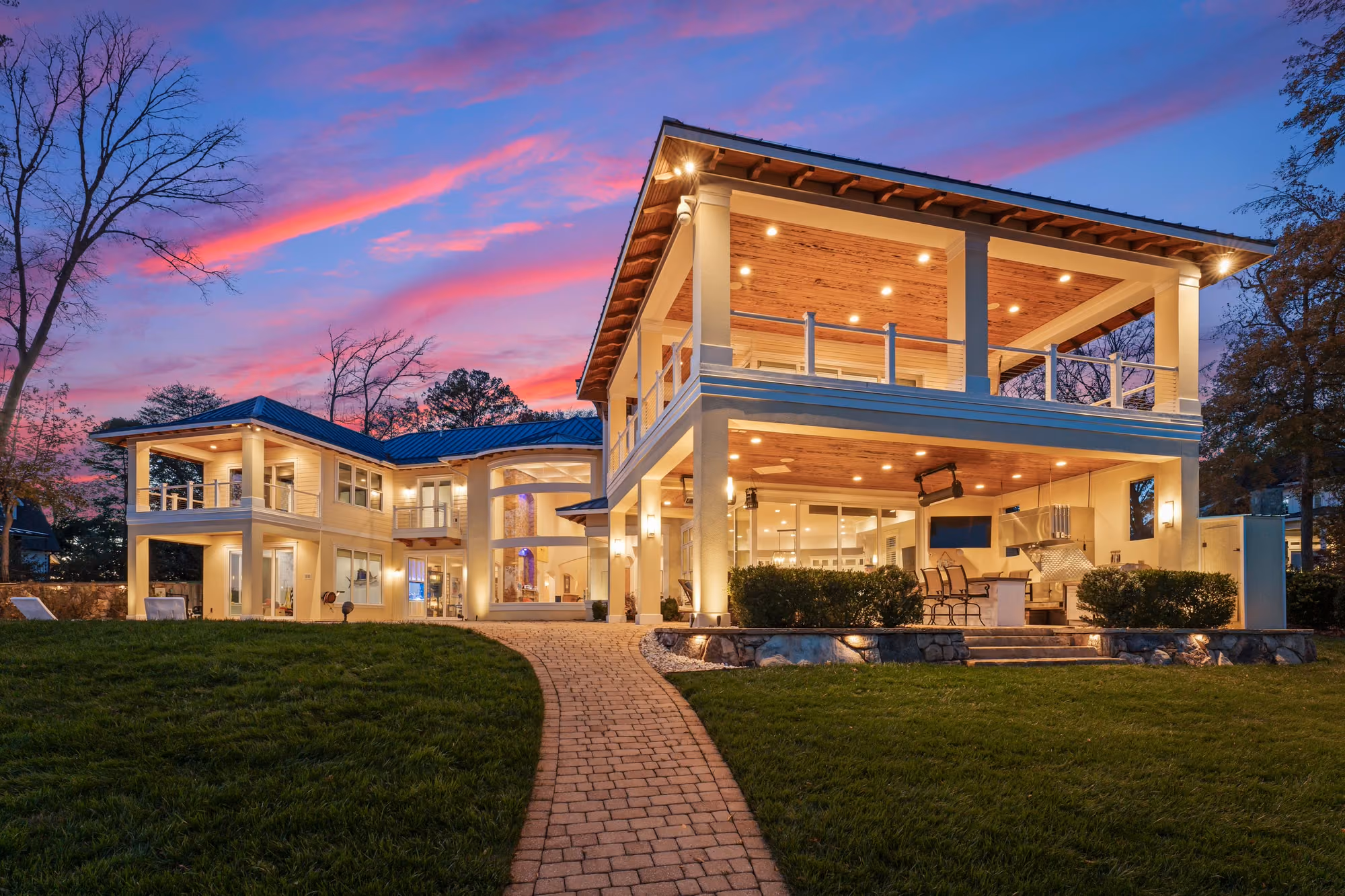A covered terrace lit from above at dusk, open to the lawn.