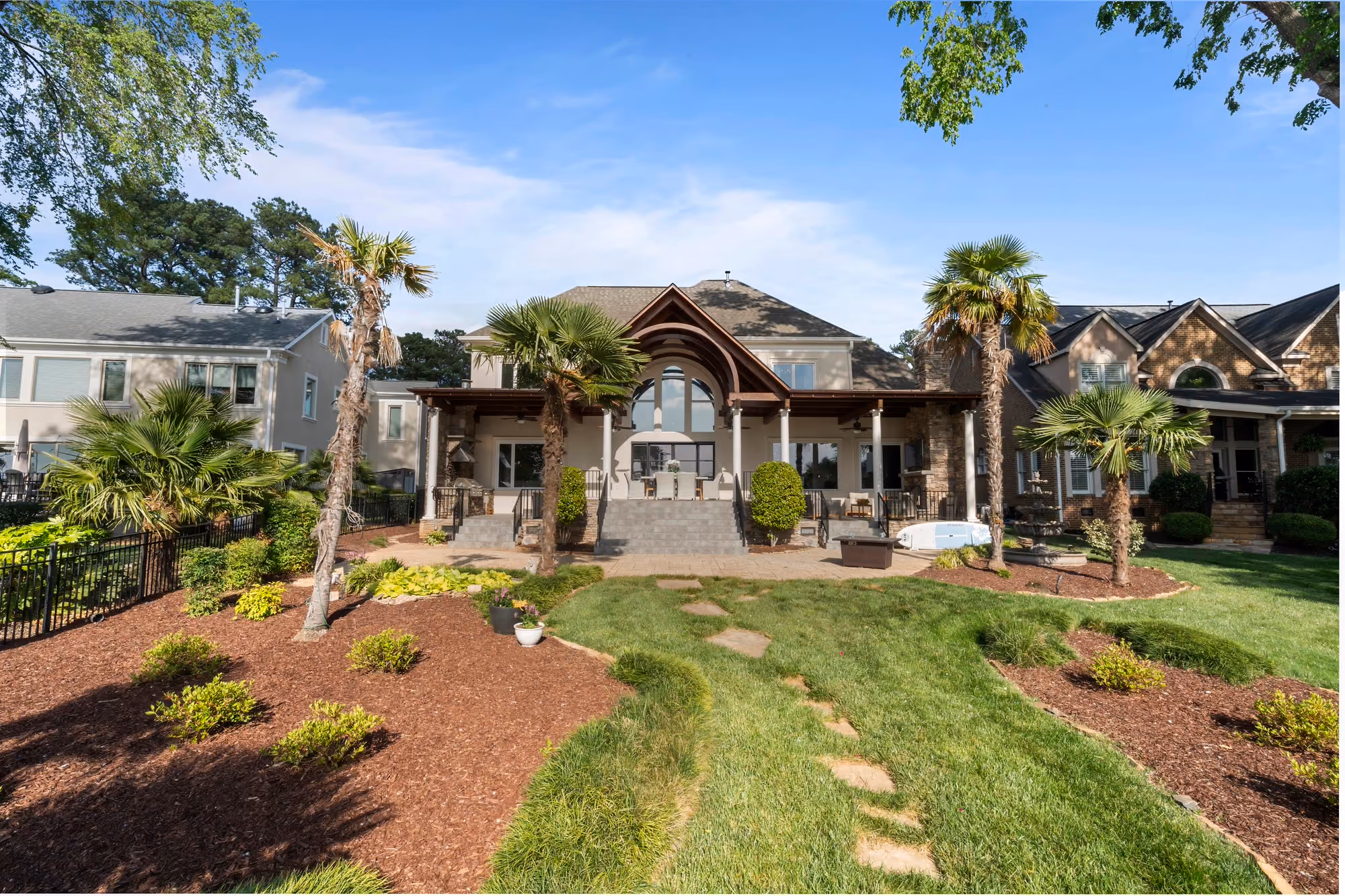 A lake house behind palms and a curving lawn.