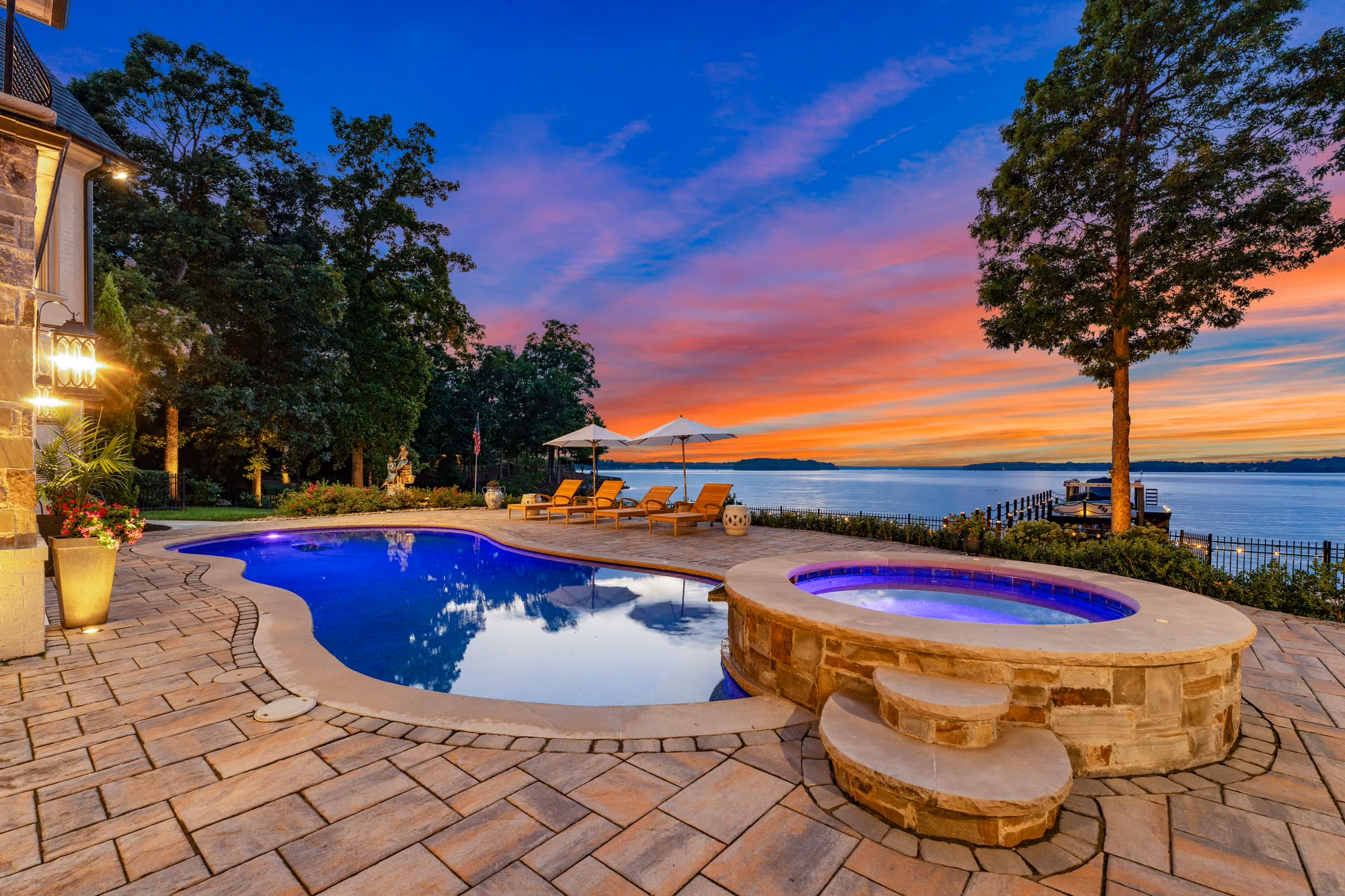 A pool and spa lit at sunset, with Lake Norman open behind them.