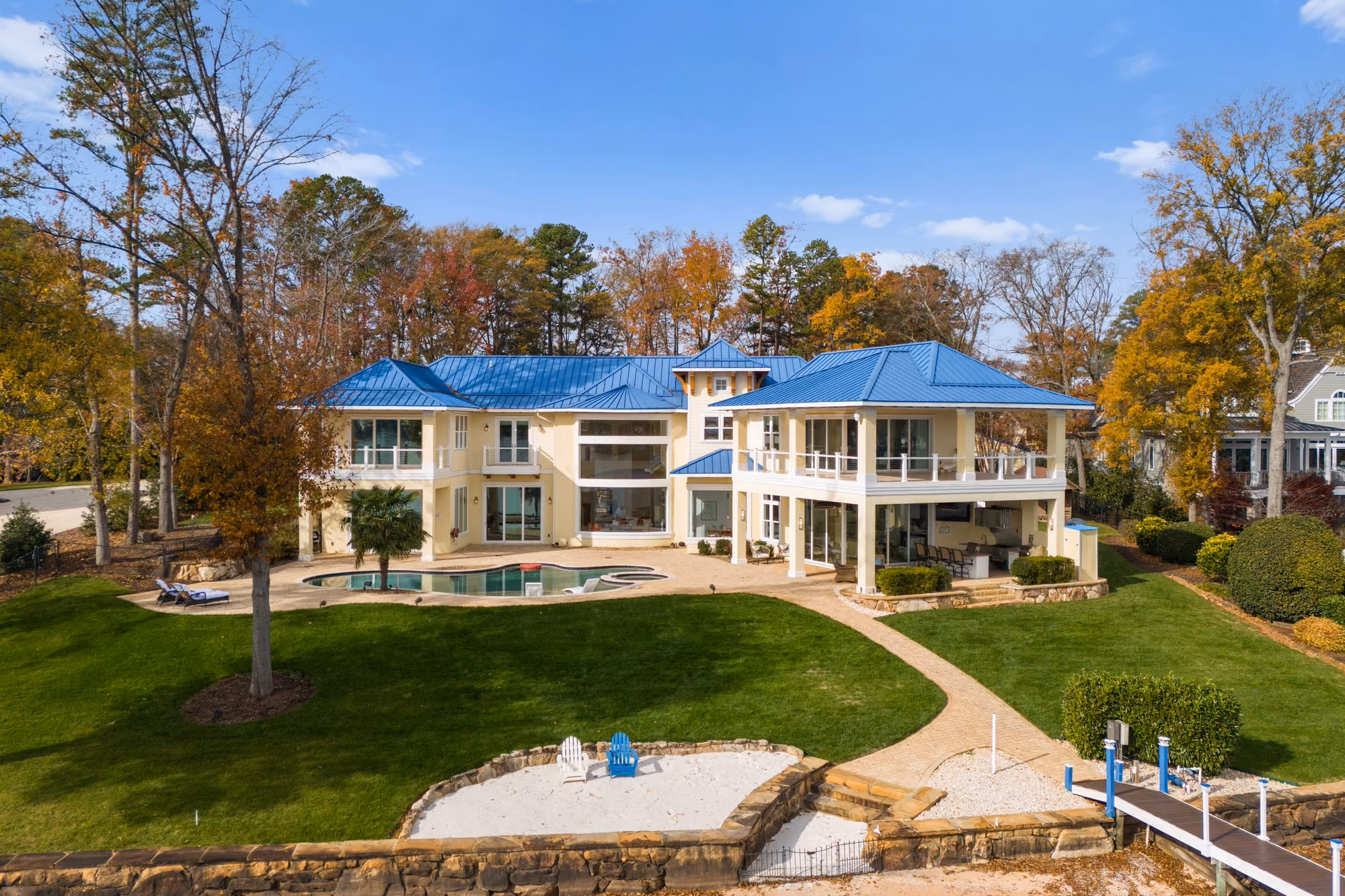 A blue roofed house, its pool and its lawn in autumn, from the air.