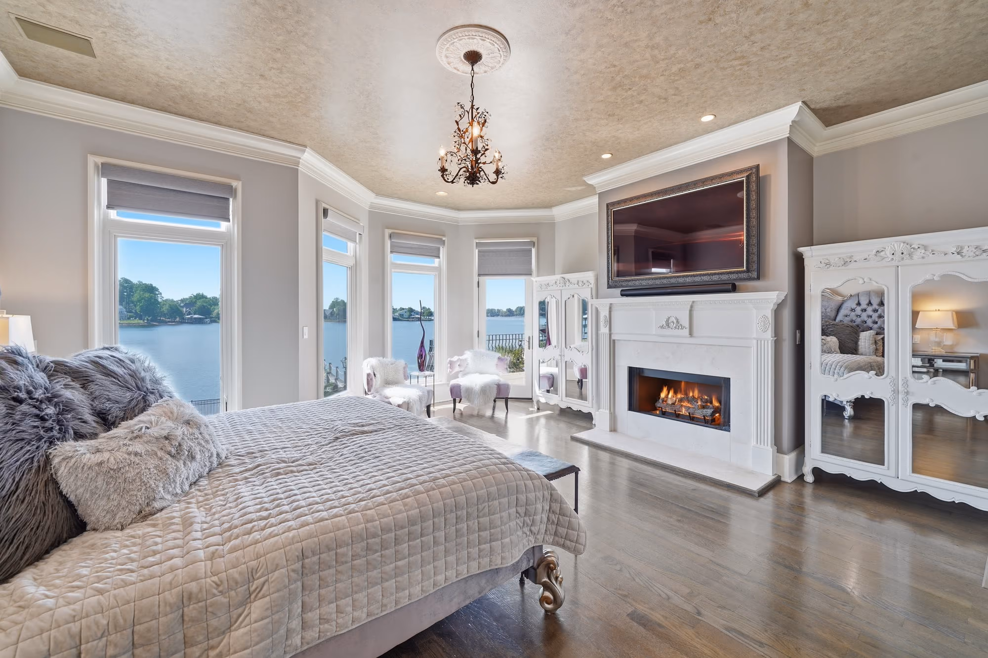 A primary bedroom with windows on three sides and the lake beyond them.