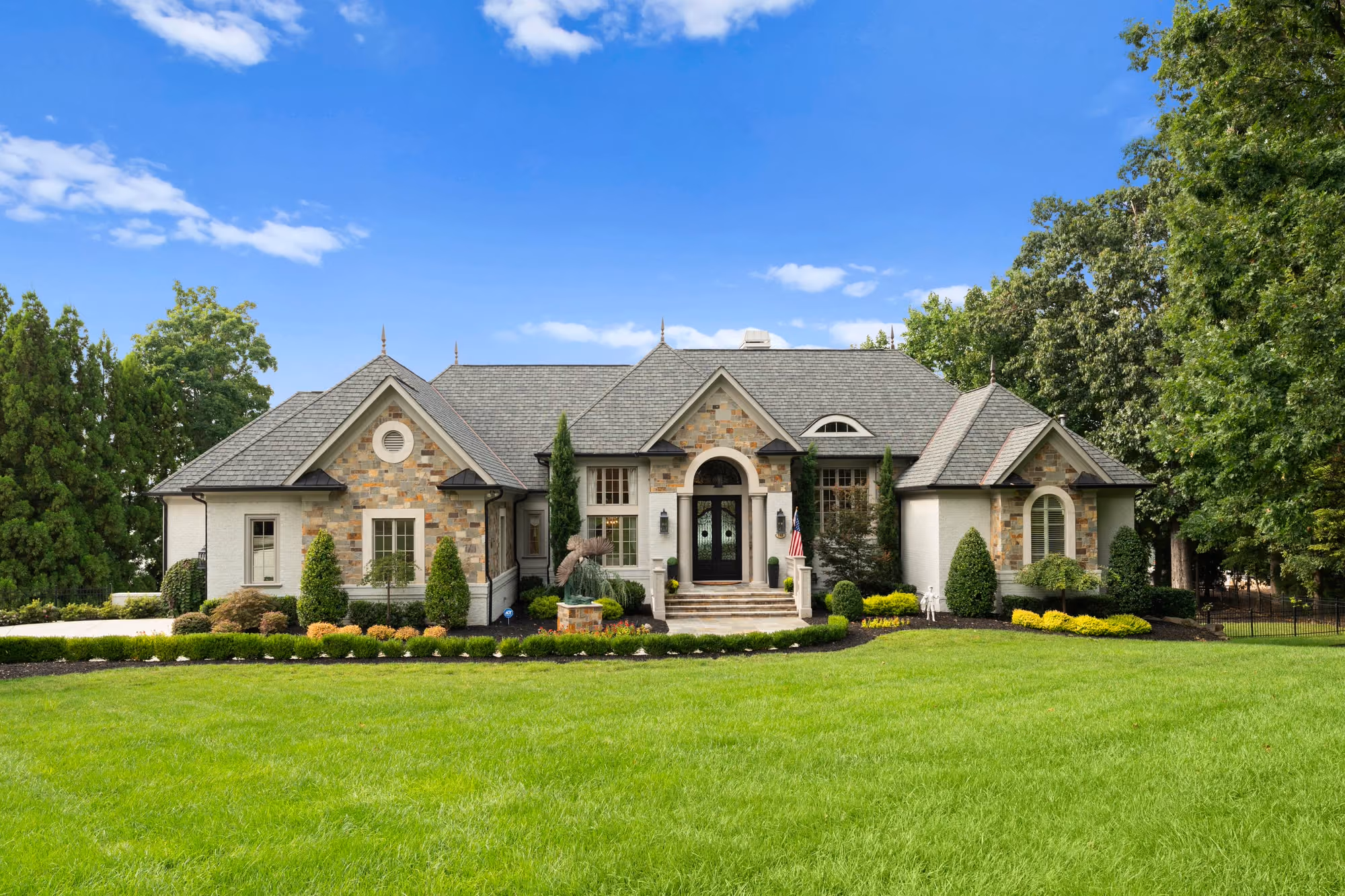 A stone and stucco front elevation across a wide clipped lawn.