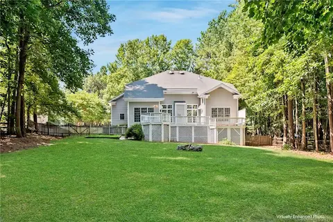 HUGE fenced in backyard, surrounded by trees and with plenty of room to run and play. Grass is virtually enhanced in this image.