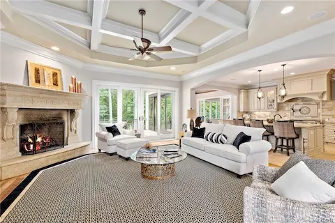 Spacious great room with hardwood floors, coffered ceiling & stone fireplace opens to a large gourmet kitchen and outdoor patio.