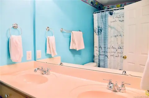 Second full bathroom with double sink and tub shower surround.