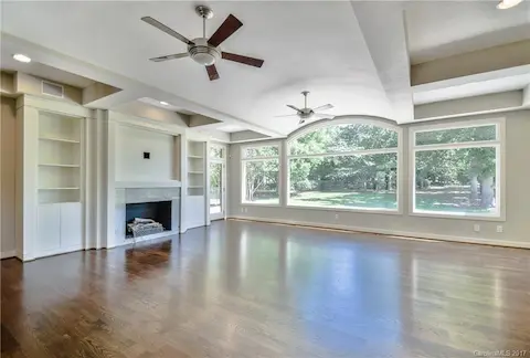 Great Room with built in shelving, gas fireplace, ceiling fans, hardwood floors & beautiful, expansive view of golf course