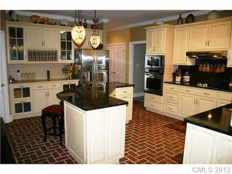 Kitchen - Granite countertops and new stainless steel appliances, custom ivory cabinets, center island with counter bar, stained glass pendant lighting above island, thin brick veneer floors in a herringbone pattern.