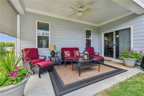 Covered patio with ceiling fan and adjustable blind.