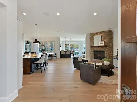 Step into a light-filled, open-concept living space where the gourmet kitchen, impressive stone fireplace, and expansive lake views create an unforgettable first impression.