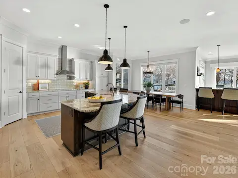 Gourmet chef's kitchen features an oversized quartz island with seating, custom cabinetry, stainless steel appliances, subway tile backsplash, and seamless flow into the dining and living areas, making it ideal for entertaining.