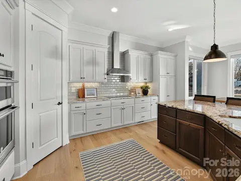 Gourmet chef's kitchen features an oversized quartz island with seating, custom cabinetry, stainless steel appliances, subway tile backsplash, and seamless flow into the dining and living areas, making it ideal for entertaining.