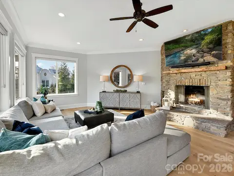 Inviting Great Room showcases a striking floor-to-ceiling stone fireplace, expansive windows with stunning Lake Norman views, and seamless access to the outdoor living spaces.