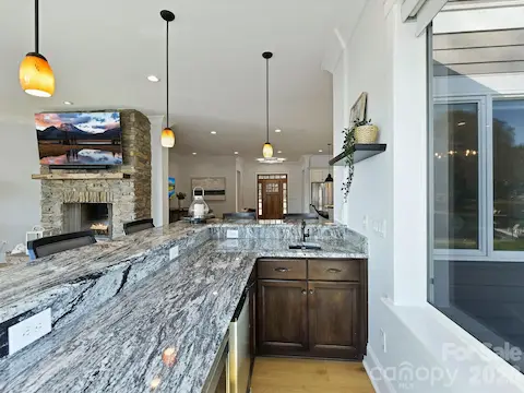 Convenient main-level wet bar with granite countertops, sink, beverage refrigerator, and serving space enhances entertaining while overlooking the open living areas and Lake Norman views.