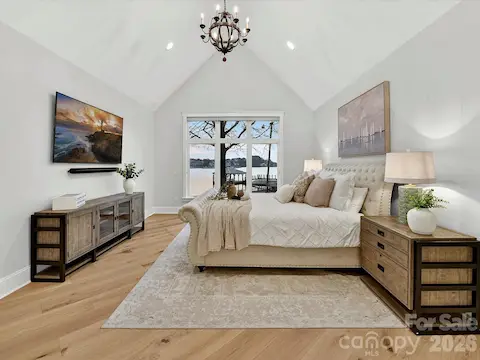 Luxurious main-level primary suite features a soaring vaulted ceiling, expansive Lake Norman views, and a peaceful retreat designed for comfort and relaxation.