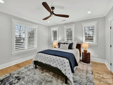 Spacious secondary bedroom features abundant natural light, plantation shutters, hardwood floors, and generous closet space for family or guests.