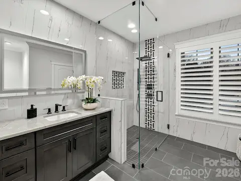 Stylish ensuite bath features a designer vanity, oversized frameless glass walk-in shower with custom tilework, and upscale modern finishes.