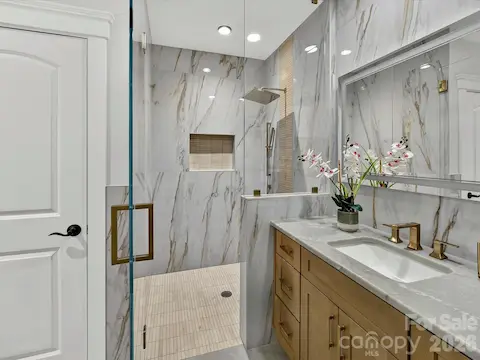 Bedroom 4 features a beautifully appointed private ensuite bath with a custom tiled walk-in shower, quartz vanity, designer finishes, and upscale fixtures.