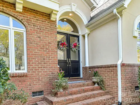 Welcoming double front door and stone stairs leading to arched entry