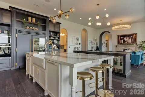 Prep island with dishwasher, trash compactor, microwave, and storage, complemented by additional island with seating, beverage fridge, ice maker, and storage. Custom cabinetry to the left houses TRUE refrigerator/freezer, WOLF steam oven, add'l wall oven, and 2 refrigerated drawers. With plenty of display space for cookbooks.