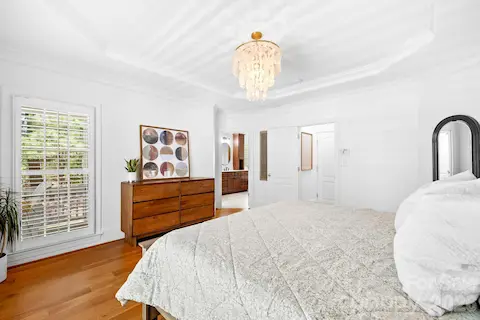 This primary bedroom has a classic elegance to it with the lovely chandelier and tray ceiling.