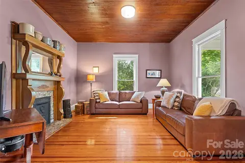 Quaint family room with wood mantel with elegant curved detailing, complemented by a classic tiled surround and decorative cast iron insert—adding timeless character and warmth to the space.
