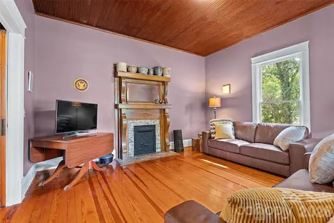 Quaint family room with wood mantel with elegant curved detailing, complemented by a classic tiled surround and decorative cast iron insert—adding timeless character and warmth to the space.