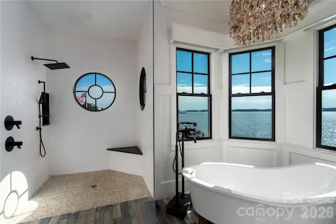 INDULGE IN PURE SPA RELAXATION! A DEEP FREESTANDING SOAKING TUB FRAMING WIDE OPEN WATER VIEWS, AN OPULENT STATEMENT LIGHT FIXTURE, CUSTOM DECORATIVE TILED WALK-IN SHOWER AND HEATED TILE FLOORS