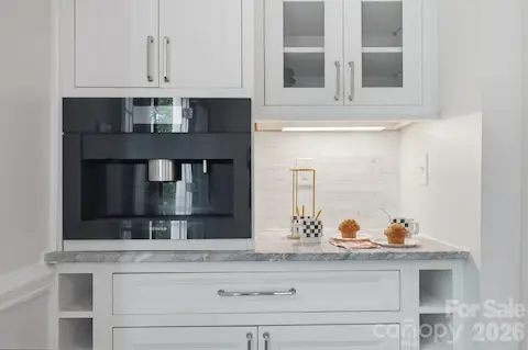 Built-in coffee and wine bar with Miele coffee maker, marble countertop, glass display cabinets and wine bottle cubbies