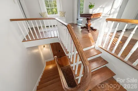 The original stairs winding switchback design, original wood treads, painted balusters, curved plaster walls, and substantial handrail.