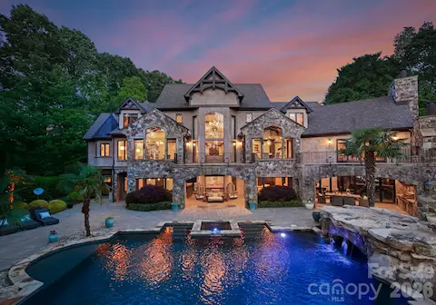 Tiered backyard with infinity-edge pool, two covered patios for dining and lounging, and stone pathways leading to the private dock.