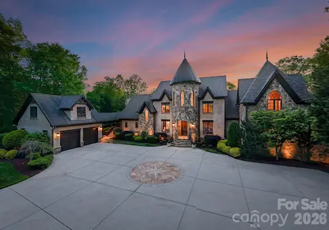 Pass through a private gate to arrive at this grand stone residence, where a nautical star design anchors the front driveway. A stately façade with arched entry and manicured landscaping warmly welcomes you home.