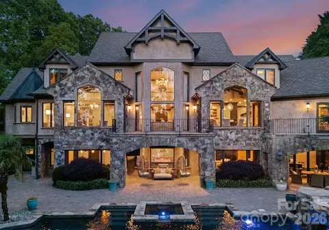 Tiered backyard with infinity-edge pool, two covered patios for dining and lounging, and stone pathways leading to the private dock.