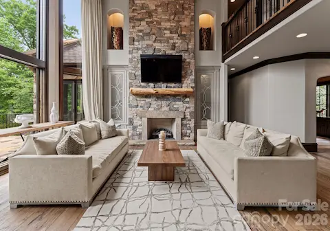 Two-story living room with fireplace, chandelier, and custom cabinetry.