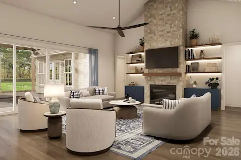 This inviting living room blends modern comfort with timeless elegance. A floor-to-ceiling stone fireplace anchors the space, flanked by built-in shelves with accent lighting and navy cabinetry for a pop of color.
