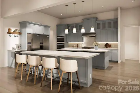 This gourmet kitchen is a perfect blend of style and functionality. It features soft blue-gray custom cabinetry, sleek quartz countertops, and a double island layout that offers ample space for meal prep and casual dining