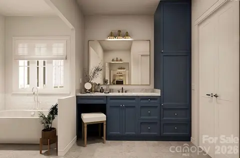 Navy blue cabinetry with marble countertops and brass fixtures adds a bold yet elegant touch, complemented by a dedicated vanity area and built-in storage tower for optimal functionality.