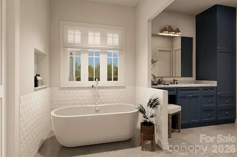This luxurious bathroom features a deep soaking tub beneath a wide window with soft Roman shades, offering natural light and privacy.