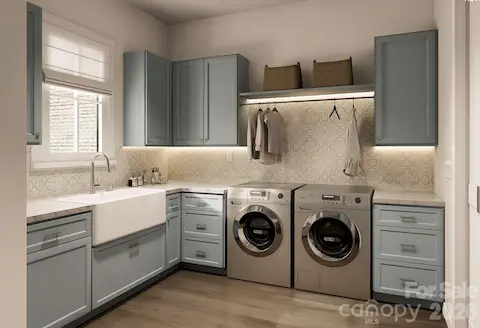 This beautifully appointed laundry room combines charm and utility with soft blue cabinetry, patterned backsplash tile, and warm wood flooring.