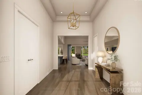 This elegant foyer sets a refined tone with its high tray ceiling, soft neutral palette, and sleek wood floors that flow seamlessly into the main living area.