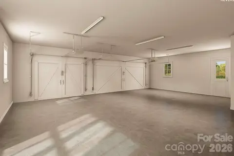 This oversized three-car garage features carriage-style doors, durable concrete flooring, multiple windows for natural light, modern openers, and a convenient side entry.