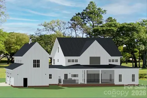 Rear view highlights its large covered porch, clean board-and-batten siding, a sleek black metal roof, and a three-car garage with a cupola-topped gable.