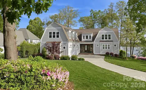 Charming waterfront home with manicured landscaping, inviting front entry, and a spacious three-car garage.
