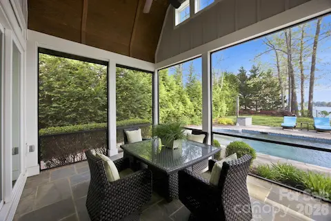Screened porch offers a covered outdoor living space with seating and views of the pool and landscaped yard.