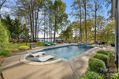 Private backyard features an in-ground pool with sun shelf, spa, expansive patio, and mature trees with water views.